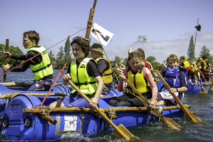 Youth in life jackets on a raft in the water during the Kon Tiki Race Raft