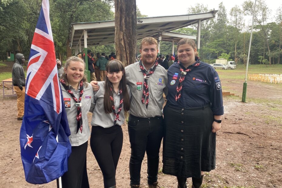 Four Rovers attend the moot in Africa pose for a photo. The Rover on the left holds the New Zealand flag.